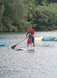 photo of Karlos using hand over hand technique to guide Petras on proper paddling technique while paddling on the river